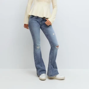 Lågmidjade bootcut jeans - Snygga blå bootcut jeans med slitningar på knäna och broderade detaljer på bakfickorna. Jeansen har låg midja och är tillverkade i klassiskt denimtyg. Perfekta för dig som gillar en avslappnad men ändå trendig look. Tall modellen. Lappen kvar!!