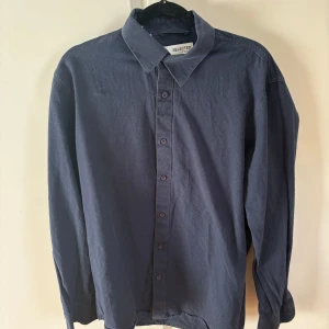 Mörkblå skjorta från Selected Homme - Säljer en stilren mörkblå skjorta från Selected Homme. Skjortan har klassisk krage, knäppning framtill och långa ärmar. Perfekt för dig som gillar en enkel och clean look.