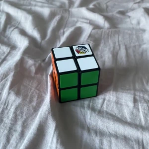 Rubik's kub 2x2 - Säljer en klassisk Rubik's kub 2x2 med vita, gröna och orangea sidor. Perfekt för dig som gillar kluriga pussel och vill träna hjärnan. Kuben är kompakt och lätt att ta med sig överallt.