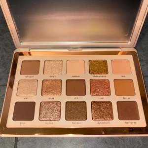 Ögonskuggspalett i varma och guldiga toner - Snygg ögonskuggspalett med 15 nyanser i bruna, guldiga och koppriga färger. Paletten innehåller både matta och skimrande skuggor, perfekt för att skapa olika looks. Kommer i en lyxig förpackning med spegel. Testat en skugga bara. Nypris 879 kr 