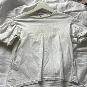 Vit t-shirt med puffärmar och pärldetaljer - Säljer en vit t-shirt med puffiga kortärmar och små pärldetaljer på ärmarna. Från Zara i storlek 152 och passar mig som har xs. 🩷