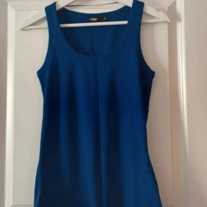 Blå ribbad linnetopp från Cubus - Säljer en blå ribbad linnetopp från Cubus. Toppen har en klassisk rund halsringning och ärmlös design, perfekt för varma dagar eller som lager under andra plagg.
