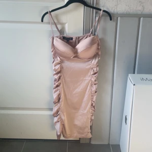 Ljusrosa satin klänning från NAKD x Kristin - Säljer en ljusrosa satin klänning med smala axelband och vadderad byst. Klänningen har rynkade sidor och figurnära passform. Den är helt oanvänd och lappen sitter kvar!🌟❣️ Storlek M/L. (Den passar mig och jag är en M) Pris går att diskutera!