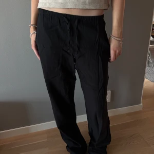 Svarta vida linnebyxor med resårmidja - Säljer ett par svarta linnebyxor med rak och lite lös passform. Byxorna har resår i midjan för extra komfort och är tillverkade i ett lätt och mjukt material. Perfekta för en avslappnad och stilren look.