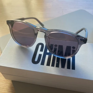 Chimi solglasögon 01 - Snygga solglasögon från Chimi i transparent färg ginger med runda glas och mörka linser. Klassisk modell med diskreta detaljer på skalmarna. Perfekt accessoar för att lyfta din stil.
