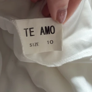 Vit axelbandslös klänning med rosmönster - Säljer en vit axelbandslös klänning med vacker rosmönstrad överdel och utsvängd kjol. Använd en gång på studenten, passar inte mig mer. Storlek XS-S. Dock så har den blivit lite missfärgad se bild där den är fått lite mörk färg men går nog bort, se även sista bild lite sliten. Inlägg i ”bhn”