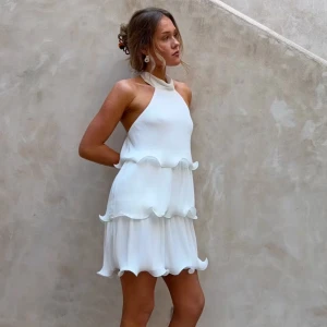 Vit halterneckklänning med volanger - Säljer en superfin vit klänning med halterneck och volangdetaljer i två lager. Klänningen har en luftig passform och är perfekt för sommarens alla tillfällen. Materialet känns lätt och svalt.