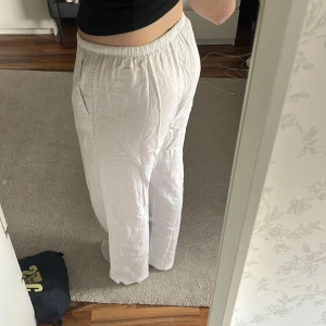 Vita linnebyxor - Säljer ett par vita linnebyxor med avslappnad passform och resår i midjan. Byxorna har dragsko och raka ben, perfekta för varma dagar. Lätta och luftiga med fickor på sidorna.