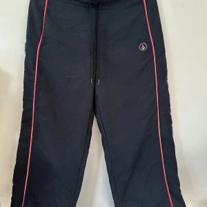 Svarta byxor med neonränder - Svarta trekvartsbyxor / friluftsbyxor / byxor med resår och dragsko i midjan. Fixa bak och färgade ränder längs sidorna och bakfickan. Supersköna byxor som andas och är lätt vattenavstötande.   Hämtas i Stockholm eller skickas mot porto. 