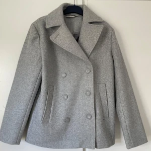 Ljusgrå kappa från Zink - Jag säljer en ljusgrå kappa i nyskick från Zink i storlek xs (32/34) som jag precis har köpt men säljer pga fel storlek, lappar sitter kvar. Jackan har dubbelknäppning med knappar framtill, krage och två fickor 💕