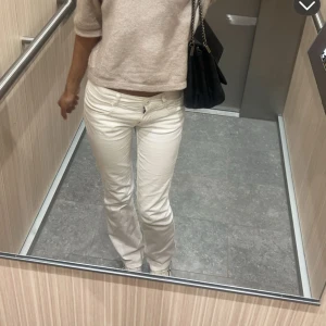 Vita bootcut jeansbyxor - Snygga vita jeansbyxor med bootcut passform och låg midja. Klassisk femficksmodell med dragkedja och knapp framtill. Perfekta att styla med en stickad tröja eller t-shirt.