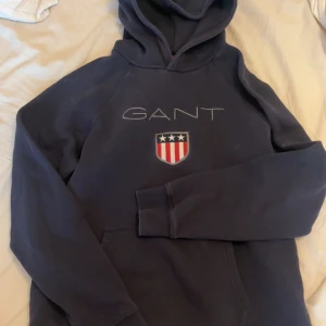 Mörkblå hoodie från GANT - Säljer en mörkblå hoodie från GANT, ficka framtill. Använd och köper för ca 2 årsen, köparen står för frakt 