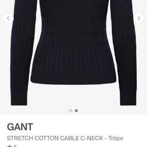 Svart kabelstickad tröja från GANT - Kabelstickad svart tröja från GANT med rund halsringning och diskret logga på bröstet. Tröjan är i stretchig bomullsblandning och har långa ärmar. Klassisk och stilren modell som passar till mycket.