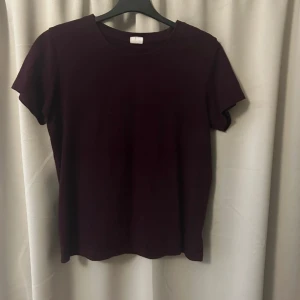 Mörklila t-shirt - En enkel och stilren mörklila t-shirt med rund halsringning och korta ärmar. Perfekt basplagg som passar till många olika outfits. Gjord i mjukt material för en bekväm känsla.