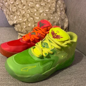 Färgglada sneakers med unikt mönster - Säljer ett par färgglada sneakers med unikt mönster. Ena skon är grön med gula detaljer och den andra är röd med orange detaljer. Båda har ett coolt fågelmotiv på plösen och snörning framtill. Perfekta för dig som vill sticka ut!