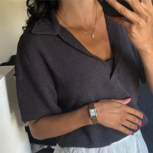 Mörkgrå kortärmad pikétröja - Säljer en stilren mörkgrå pikétröja med korta ärmar och klassisk krage. Perfekt för en avslappnad men ändå snygg look. Tröjan är tillverkad i ett mjukt och bekvämt material.