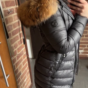Svart dunjacka från Hollies - Säljer en svart dunjacka från Hollies med en stor, fluffig pälsdetalj på huvan. Väldigt fin utan defekter.