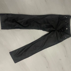 Svarta byxor med knappar - Snygga svarta byxor med knappar och dragkedja. De har en rak passform och är perfekta för en stilren look. Passar bra till både vardag och mer uppklädda tillfällen.