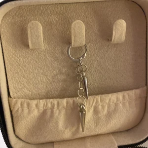 Silverfärgat örhänge med hängande detaljer - Snyggt silverfärgat örhänge med två hängande konformade detaljer. Perfekt för att ge en edgy touch till din stil. Lätt att matcha med andra smycken.