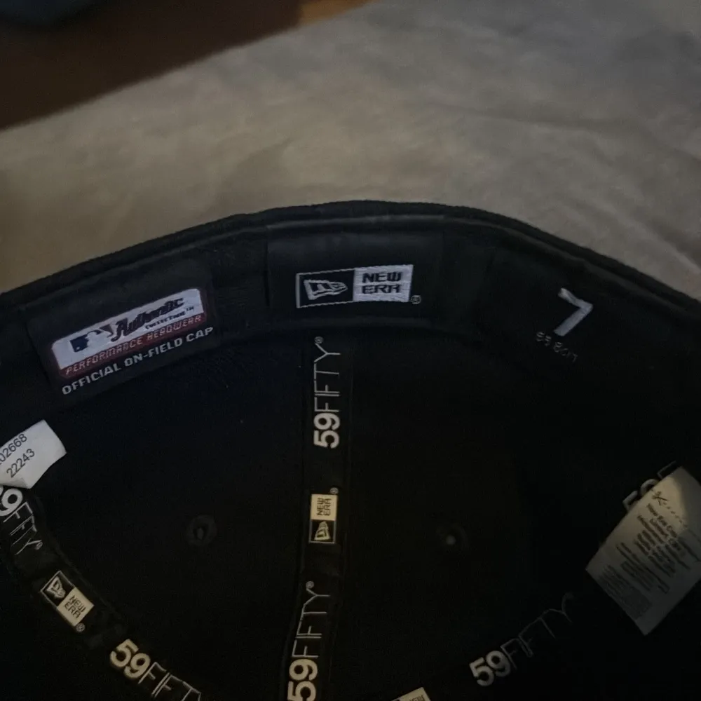 Snygg svart keps från New Era med broderad vit logotyp på framsidan. Kepsen är en 59FIFTY-modell och har en platt skärm. Perfekt för att ge din outfit en sportig touch.. Asusteet.