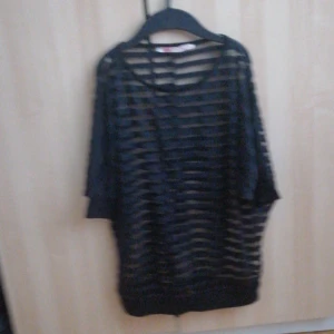 Svart randig topp från Very Nice - Säljer en svart randig topp från Very Nice. Den har en lös passform och korta ärmar. Perfekt för en avslappnad stil med sitt genomskinliga material och unika design.