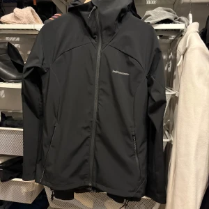 Svart jacka från Peak Performance - Säljer en stilren svart jacka från Peak Performance. Jackan har en praktisk huva och dragkedja framtill. Perfekt för utomhusaktiviteter och vardagsbruk.