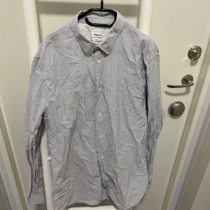 Randig skjorta från Filippa K - Säljer en stilren randig skjorta från Filippa K i storlek medium. Skjortan har en klassisk krage och knäppning framtill. Storlek M