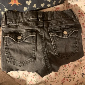 Grå jeansshorts från Gina Tricot - Snygga grå jeansshorts från Gina Tricot med klassisk femficksdesign och knappgylf. Shortsen har en cool, avslappnad stil med råa kanter och dekorativa knappar på bakfickorna. Perfekta för en casual look! Priset kan diskuteras, och jag sydde om de till shorts ( de var jeans innan) storleken är runt 158 •Barnstorlek• . Kontakta gärna för fler bilder! Jag har dock inga bilder på när de är på , för att storleken är en för liten för mig!❤️❤️