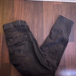 Nudie jeans!  - Snygga svarta jeans från Nudie med klassisk femficksdesign. De har en rak passform och är perfekta för en stilren look. Jeansen har en diskret tvätt för en modern touch. Storleken på de är W32 L32 och modellen är ”lean dean”