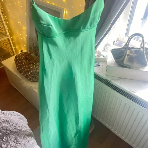 Lång grön satinklänning - Lång satinklänning i en otrolig grön färg. Klänningen är från Zara och är i storlek XS. Den är perfekt för sommaren, mottagningar eller andra festligheter. 