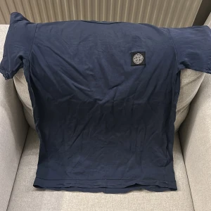 Mörkblå t-shirt från Stone Island  - Säljer en snygg mörkblå t shirt från Stone Island. Den är i strl XS-S. Som ni ser så är den bra skick förutom deffekterna på bild 3. Däremot är de två små hål som man knappt märker av. Nypris 1000 kr, mitt pris 330👍🏻💯. Vid frågor hör av er!