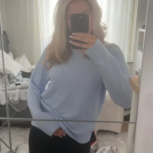 Ljusblå stickad tröja - Mysig ljusblå stickad tröja med långa ärmar och en avslappnad passform. Perfekt för kyligare dagar och ger en stilren look. Enkel att matcha med olika outfits.