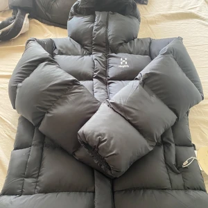 Svart pufferjacka från Haglöfs - Säljer en svart pufferjacka från Haglöfs. Jackan har en hög krage och dragkedja framtill. Perfekt för kalla dagar med sin vadderade design som håller värmen. Den har en stilren look och är ett måste för vintern. STORLEK S men passar M.  Den har tags kvar. SÄLJS FÖR 1500 kr