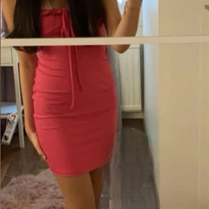 Rosa ribbad klänning - Snygg rosa ribbad klänning med knytband framtill. Klänningen har en tight passform och är ärmlös, perfekt för sommarens varma dagar. 