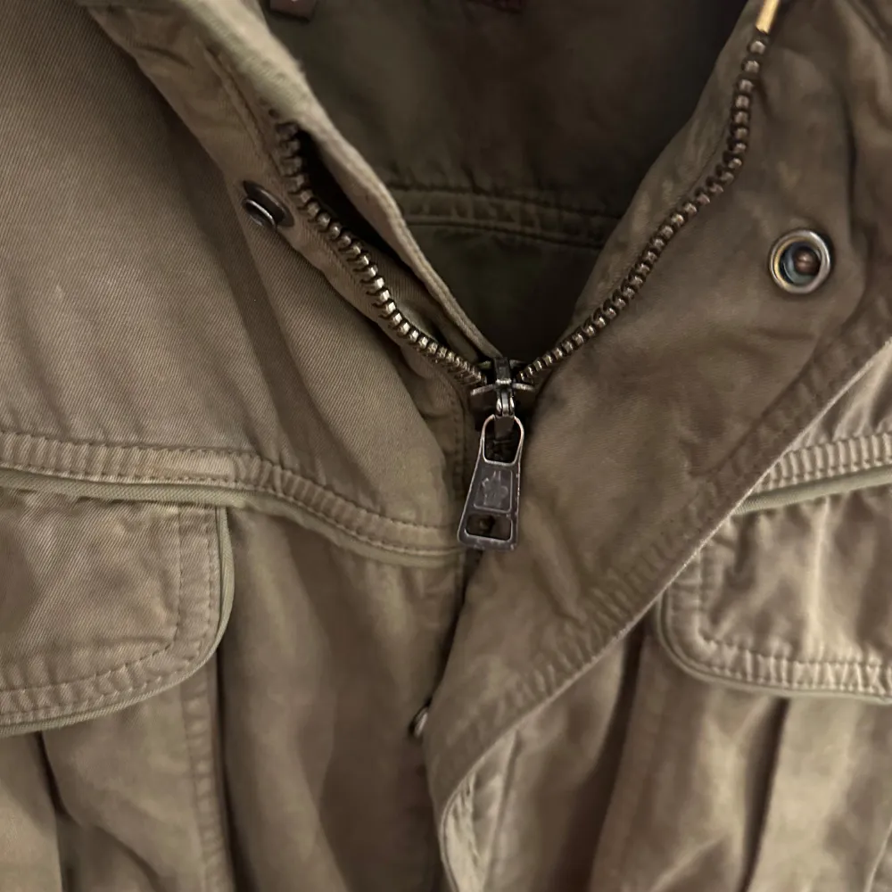 En Grön Fieldjacka från Moncler, jackan är en size 3 vilket motsvarar ungefär en M. Jackan är producerad under tidigt 2000-tal (därav brun label) och är införskaffad på Garmsmarket som garanterar äkthet. Den är inte fodrad och passar därför vår sommar bäst. Jackan är i 7/10 cond och tvättas självklart innan frakt. . Takit.