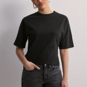 Svart croppad topp med knyt - Snygg svart croppad topp med korta ärmar och knytning i ryggen. Perfekt för en trendig look.