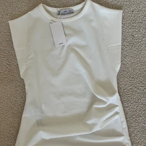 Vit topp - Säljer en stilren vit ärmlös topp från MNG. Lappen är fortfarande på! Perfekt för en minimalistisk look. Toppen har en rund halsringning och är tillverkad i ett mjukt material.