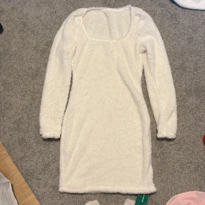 Vit fluffig klänning från Shein - Säljer en supermjuk och fluffig vit klänning från Shein. Klänningen har långa ärmar och en tight passform som ger en snygg siluett. Storlek S och endast provad. 🐑✨