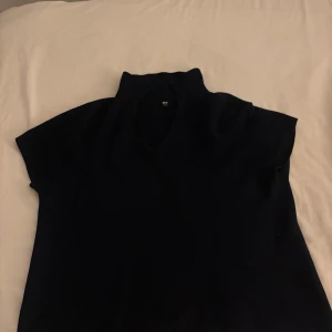mörk blå kortärmad tröja från uniqlo - Tröjan har en hög krage och korta ärmar, perfekt för en minimalistisk look.tröjan är i L men passar lika bra med mig som har storlek s.  Passar bra till både jeans och kjol. Perfekt för höst och vår! 