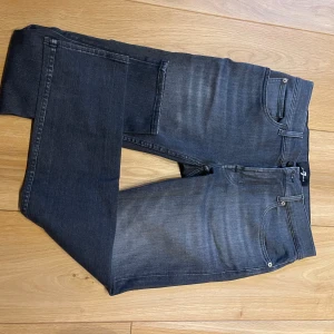 Mörkgrå jeansbyxor från 7 For All Mankind - Snygga mörkgrå jeansbyxor från 7 For All Mankind med klassisk femficksdesign och diskreta slitningar framtill. Jeansen har raka ben och normal passform, perfekta till vardags. Stängs med dragkedja och knapp.