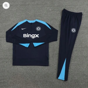 Chelsea träningsset långärmad - Chelsea FC träningsset med långärmad tröja och byxor. Setet är mörkblått med ljusblå detaljer, Nike-logga och Chelsea-emblem. Tröjan har dragkedja vid halsen och Bingx sponsortryck på bröstet. Byxorna har smal passform och klubbmärke.