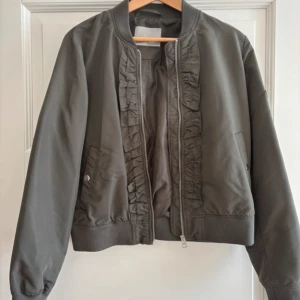 Bomberjacka med volang - Så fin bomberjacka med volanger i bra skick! Perfekt till våren!