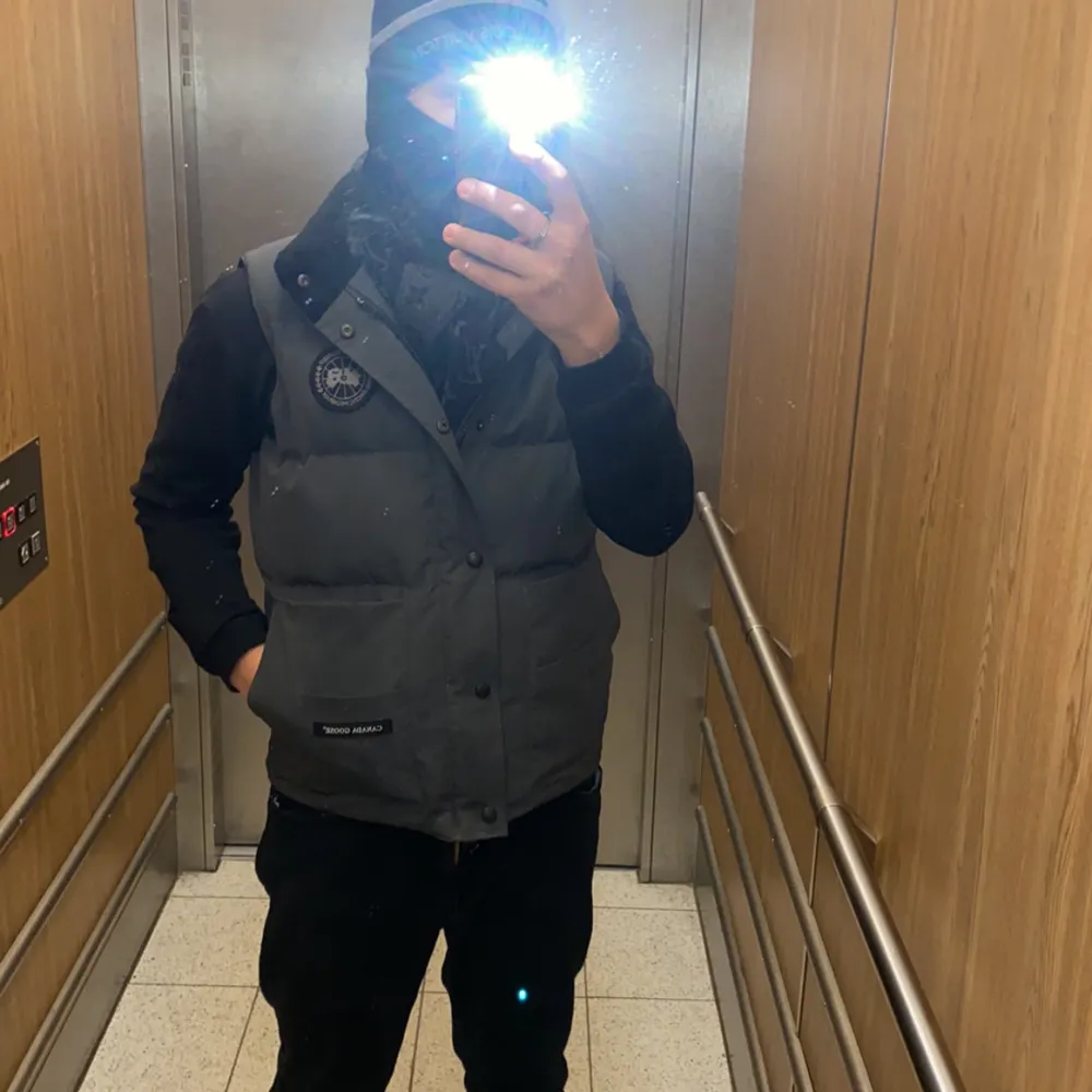Säljer en grå dunväst från Canada Goose med klassisk logotyp på bröstet och knappar framtill. Västen har två stora fickor och är perfekt för lager-på-lager. Stilsäker och varm för kyliga dagar byte kan tas imot hör av sig vid frågor eller intresse!. Takit.