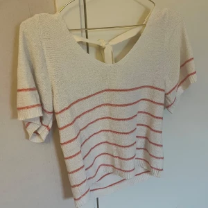 Vit stickad topp  - Säljer en vit stickad topp från JDY med röda ränder. Toppen har v-ringning och knytning i ryggen för en söt detalj.🩷