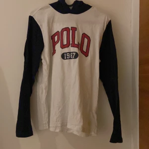 Ralph lauren hoodie - Säljer en vit och marinblå hoodie från Polo med texten 'POLO 1967' i rött och blått på framsidan. Tröjan har långa ärmar och en bekväm huva. Perfekt för en avslappnad stil.