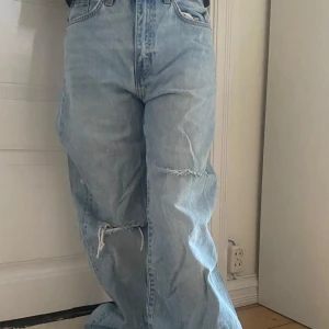 Ljusblå baggy jeans - Baggy ljusblå jeans med hög midja och raka, vida ben. Jeansen har slitna detaljer och hål på båda benen för en avslappnad och trendig look. Perfekta för dig som gillar en loose fit och streetstyle. Från lager 157,