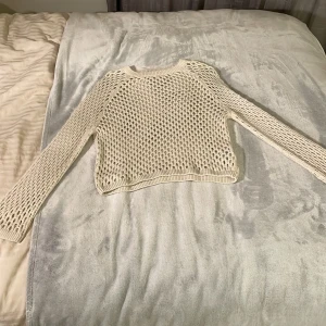 Vit stickad meshtröja från BikBok - Säljer en vit stickad meshtröja från BikBok i storlek XS. Tröjan har lång ärm och ett öppet, nätliknande mönster som ger en cool och luftig känsla. Perfekt att styla över ett linne eller topp.