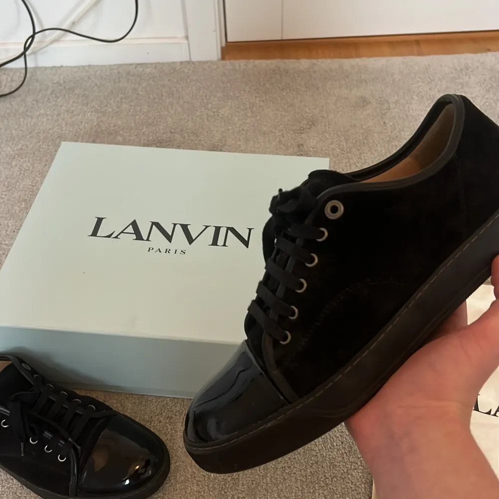 Säljer ett par svarta sneakers från Lanvin med snygg lackad tå och ovandel i mocka. Skorna har svarta skosnören, rund tå och platt sula. Kommer med originalkartong, dustbags och extra skosnören. Det vill säga allt og hänger med. Om ni vill ha mer bilder eller har några funderingar är det bara att kontakta mig.. Kengät.