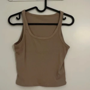 Beige ribbad linnetopp - Säljer en beige ribbad linnetopp med rund halsringning. Toppen är ärmlös och har en croppad passform, perfekt för varma dagar. Enkel och stilren design som passar till mycket.