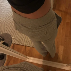 Grå mjukisbyxor från Juicy Couture - Säljer ett par grå mjukisbyxor från Juicy Couture med fickor framtill och där bak med knappar. Byxorna har normal passform och är perfekta för en avslappnad stil. Mjukt material och klassisk design.